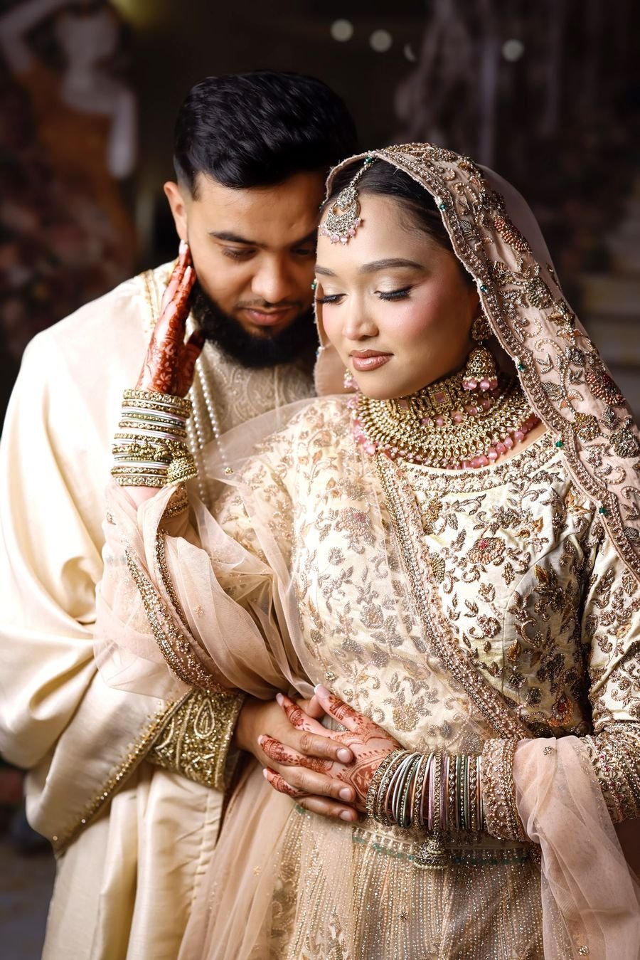 Groom embracing his bride in gold bridal jewellery