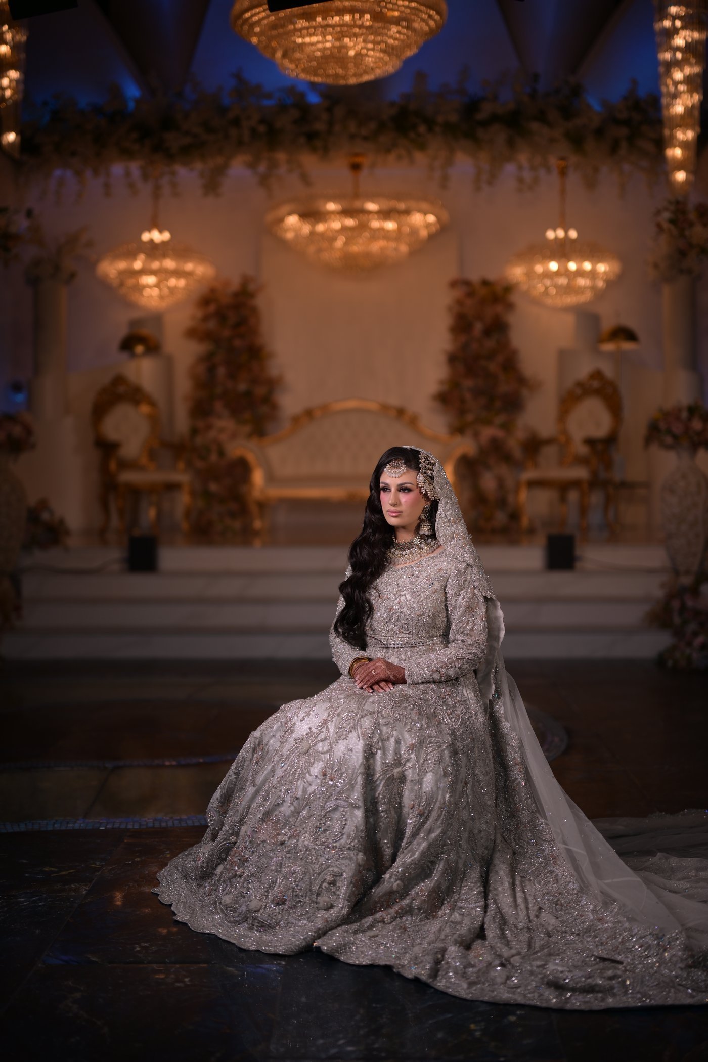 Bride seated on the stage at The Balmayna, beneath the chandeliers
